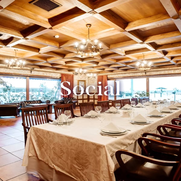 Long dining table set for a banquet in a spacious room with large windows and wooden ceiling.