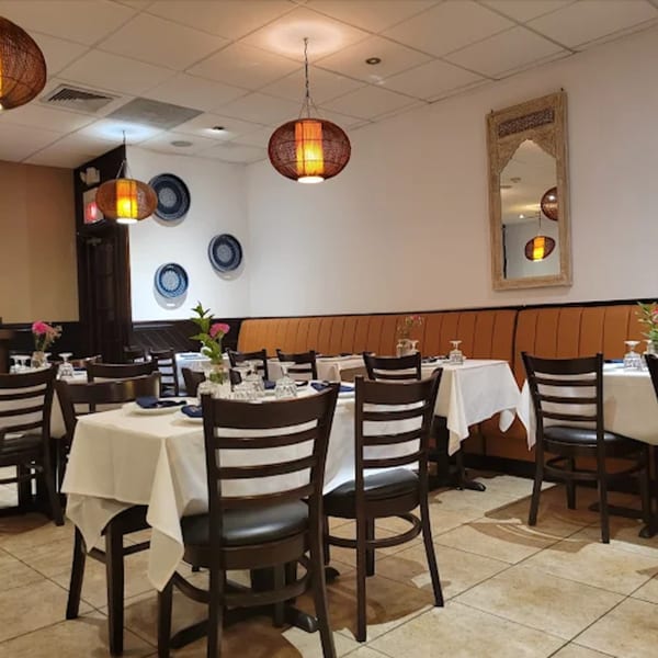 Interior of Neelam Indian Cuisine, featuring dining tables with white tablecloths, chairs, and warm lighting.
