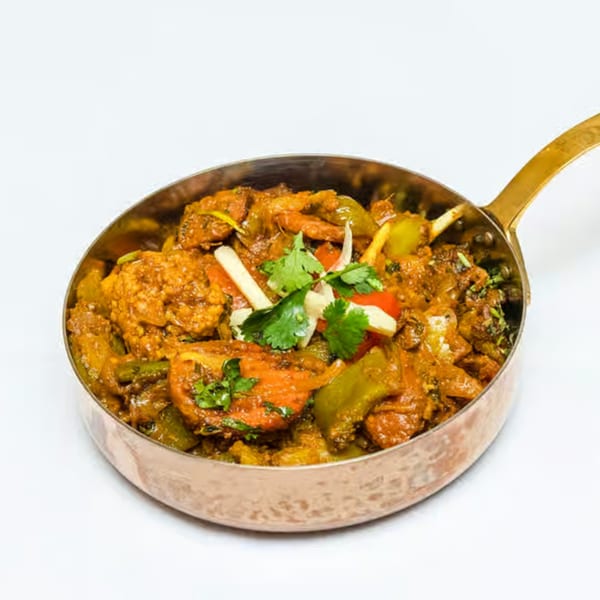 Neelam Indian Cuisine's colorful Indian curry with vegetables and cilantro in a copper pan.