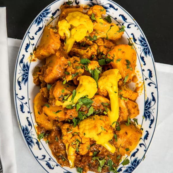 Aloo Gobi, an Indian dish with potatoes and cauliflower in a rich, spiced sauce, garnished with cilantro.