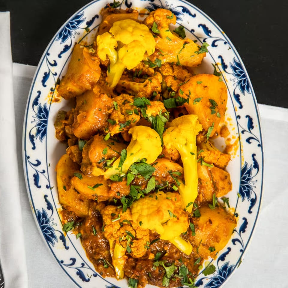 Aloo Gobi, an Indian dish with potatoes and cauliflower in a rich, spiced sauce, garnished with cilantro.